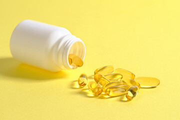 Closeup of a lot of omega 3 oil capsules and a plastic container.