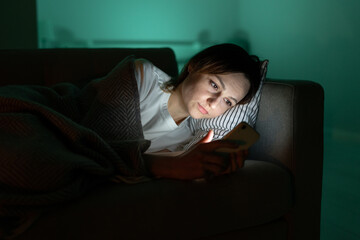 Young woman surfing internet in dark room at night. Addicted millennial female suffer from gadget...