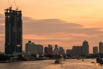 Bangkok, 17 January 2017, The view point of Chao Phraya River and the boat in motion in the night taken from Saphan Taksin Bridge in warm tone, this view wall called "Eye of Bangkok".