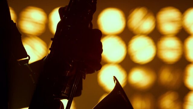Musician hands playing saxophone jazz club closeup. Silhouette player hold sax.