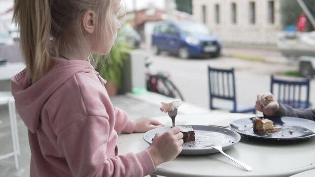 A cute little girl eats a piece of chocolate cake in a cafe in Turkey.