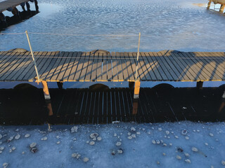 wooden pier on a river covered with ice in winter