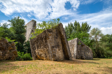 Ruins of the bridge of Augustus, Narni on the Nera river in Umbria. Used to cross the particular gorge of the Roman ruins in marble and stone, in the archaeological park on a summer day.