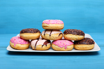 Mix of multicolored doughnuts with sprinkles on blue background.