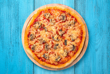 Pizza with tomatoes, mushrooms, cheese and tomato sauce on a blue background.