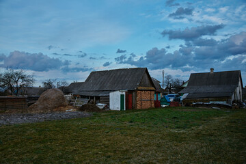 Old rural house with barns with green field blue sky and clouds at sunset