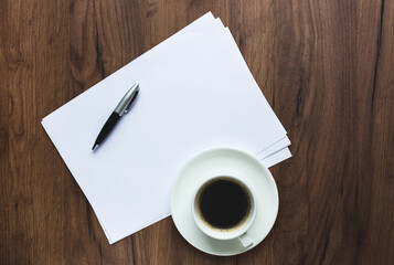 office desk with white sheets, pen and glasses.