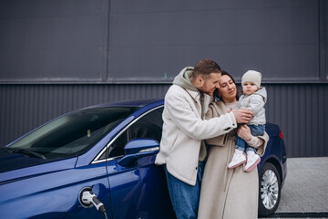 A young, happy family charges an electric car