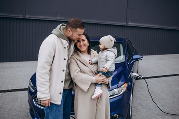 A young, happy family charges an electric car