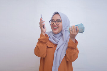 cheerful muslim woman holding indonesian money and phone