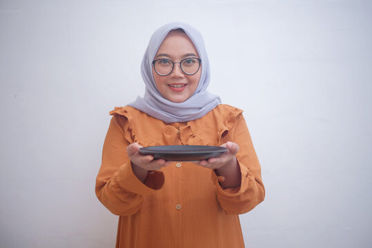 asian muslim woman holding empty plate isolated in white