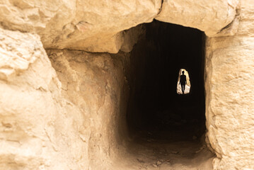 Anonymous woman in dark cave through mountain