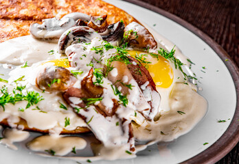 pancake with mushroom sauce, bacon and egg on plate