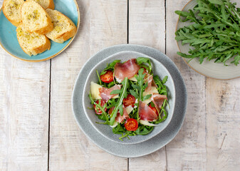 Salad with Parma, prosciutto ham, arugula and Parmesan. Black background, top view. Flat lay