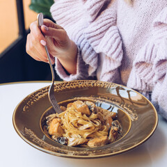 Woman is eating tagliatelle pasta in a restaurant