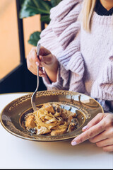 Woman is eating tagliatelle pasta in a restaurant