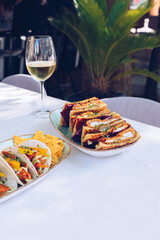 Fototapeta na wymiar Lunch with katsu sando, tacos and a glass of wine.
