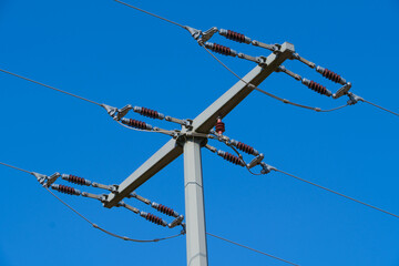 Stromleitung mit Kabeln und Isolatoren an einem Strom-Mast bei einem blauen Himmel