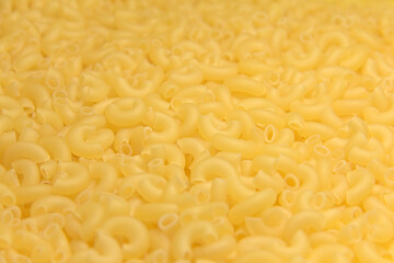 Dry raw yellow pasta. Completely background. Close up.