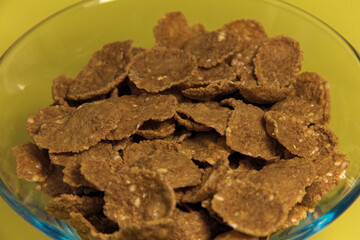 Flakes in a transparent plate. On a yellow background. Close up.