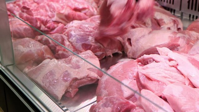 Close-up of salesman lays out the the raw red meat on the window display in grocery department at supermarket, 4k footage