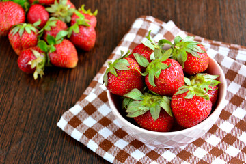 fresh strawberries in pink bowl on brown tablecloth, close-up