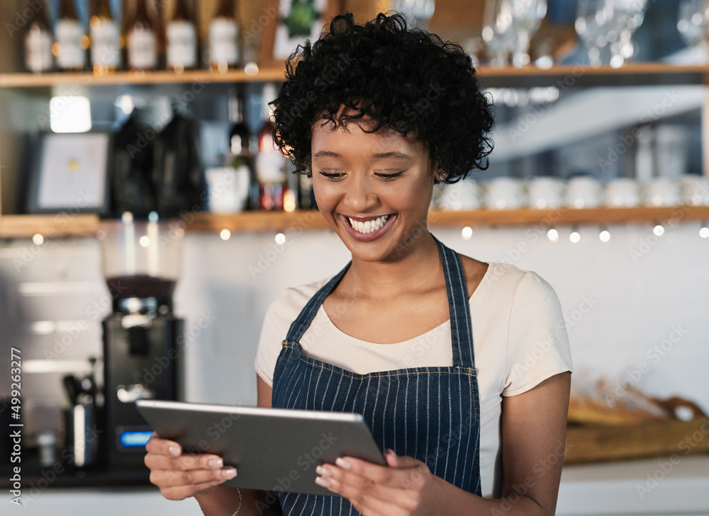 Poster Taking advantage of technological tools to boost sales. Shot of a young woman using a digital tablet while working in a cafe.