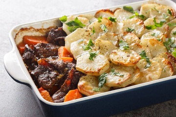 Lancashire Hot Pot, lamb and vegetables topped with sliced potatoes and oven baked closeup in the baking dish on the table. Horizontal