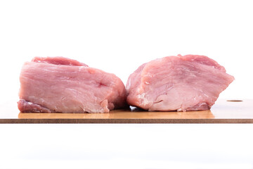 Cutting board with pieces of raw meat over white background.