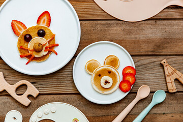 Funny food for kids. Bear and cat made of pancakes with strawberries. Idea for a baby breakfast. Top view, flat lay