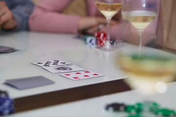 Poker table with chips, cards, glasses of champagne on the table with reflection. Enjoying the moment with friends, digital detox. Lifestyle photography. Candid moment. Selective focus.