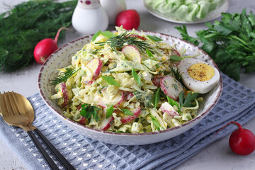 Salad with cabbage, radishes, parsley, chives, eggs, and sour cream on a gray background. Healthy food