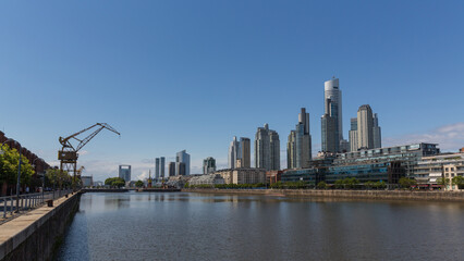 Wolkenkratzer in der Hafenstadt von Buenos Aires mit den gläsernen Fassaden vor dem seichten Wasser der Hafeneinfahrt.