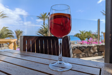 Enjoying a glass of sangria in the shade of a restaurant overlooking the sea, flowers and palm trees while on vacation