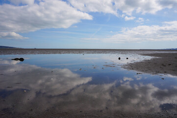 A mirror-like reflection of clouds on the seashore.