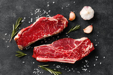 Raw meat beef steak with seasoning. Fresh striploin and bone-steak top view