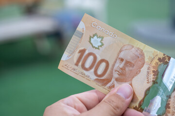 Close up of red Canadian hundred (100) dollar bill with blurred defocused background. Macrophotography.