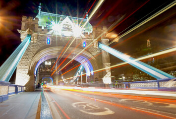 A night scene of Tower Bridge with traffic streaking by in a blur.