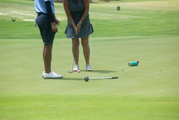 A mature woman with her personal trainer practices on the golf course in Mexico