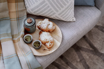 Homemade croissant and hot chinese tea in small cups on cozy couch
