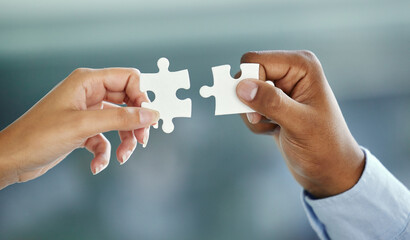 Putting the pieces together. Cropped shot of two unrecognizable businesspeople fitting puzzle...