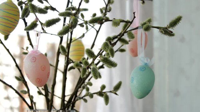   Easter home decoration in soft pastel colors . Easter floral arrangement , bouquet with willow branches and easter eggs in cozy spring home interior stands at an open window on a warm spring day.