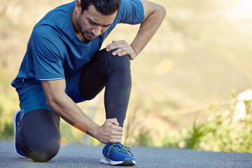 I need better running shoes. Shot of a handsome young man kneeling and suffering from a sprained...