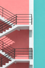 Sunlight and shadow on surface of fire escape outside of colorful pastel building in vertical frame