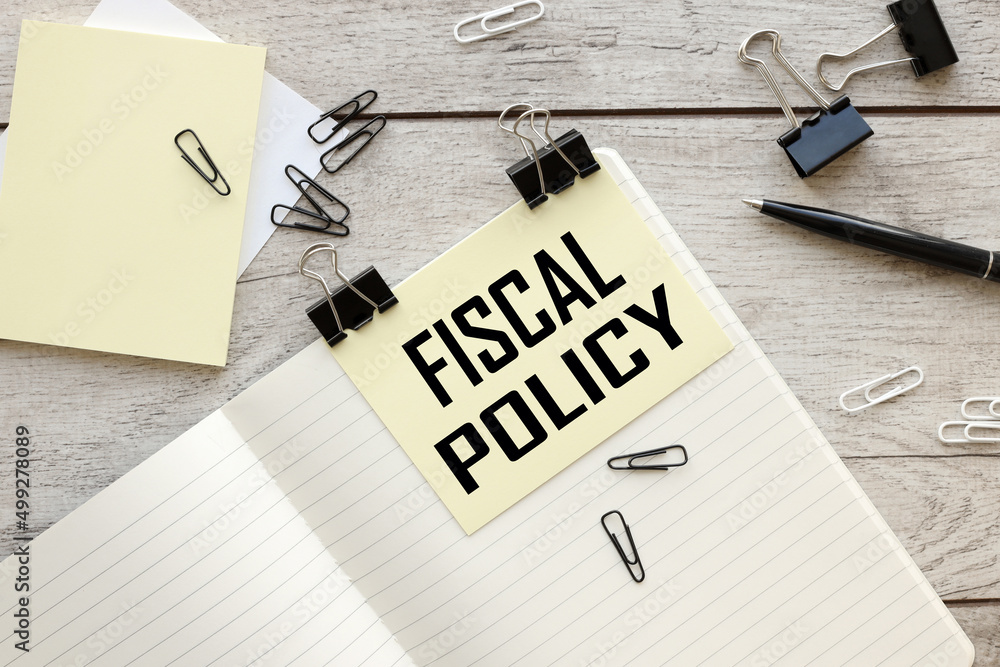 Poster fiscal policy text on yellow sticky note on notepad on desktop