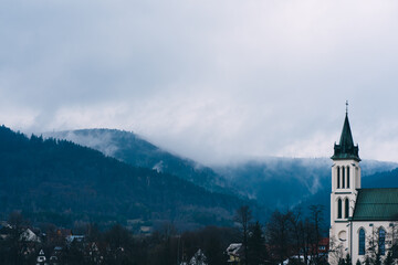 church in the Polish city of Mszana Dolna against the mountains and clouds - obrazy, fototapety, plakaty