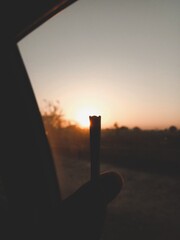 sunset smoke session smoke pot person man holding cannabis pre-rolled blunt joint marijuana weed on...