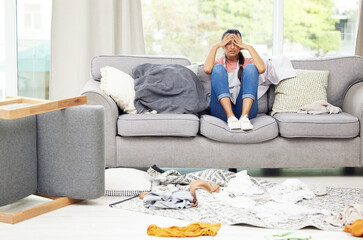 I just want to chill. Shot of a young woman feeling overwhelmed while sitting in a messy living...