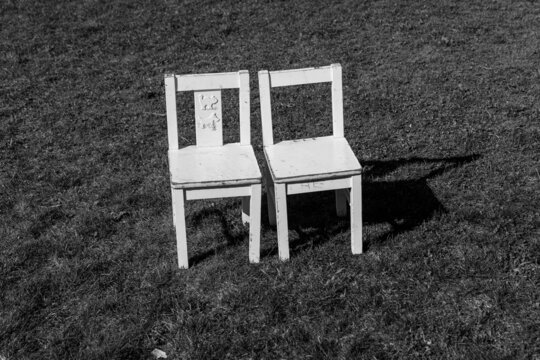 Zwei kleine weiße Stühle stehen im Gras