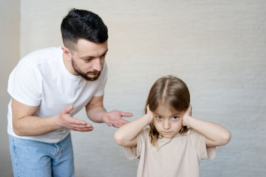 Child not listening to her father.  Parent trying authoritarian discipline method being ignored by the kid.